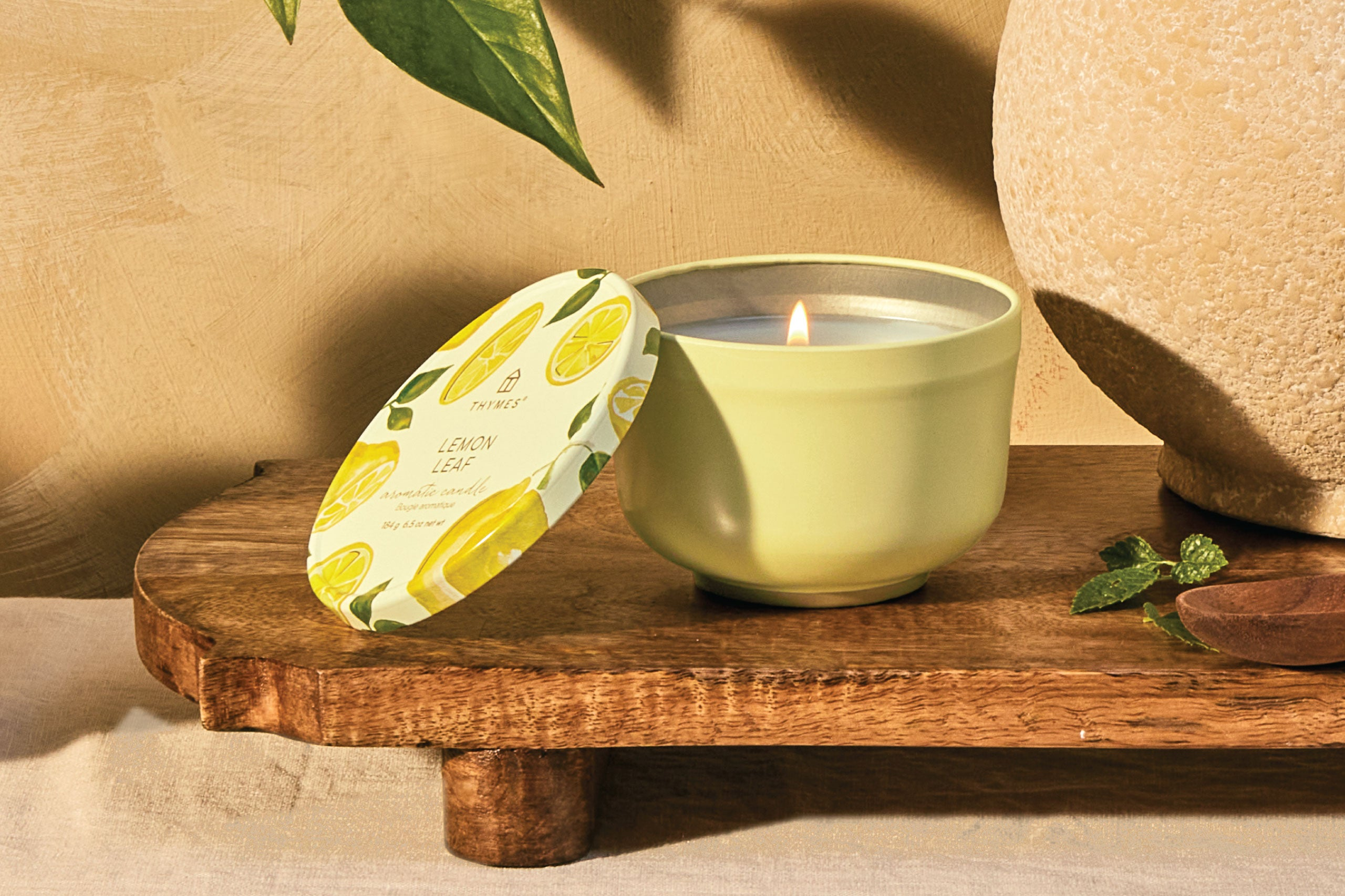 Magnolia Willow candle sitting on wooden end table with books and vase.