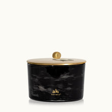 Black marbled candle jar with a gold lid on a white background, featuring the Thymes logo.