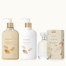 Thymes Goldleaf skincare products including body wash, cream, and perfume on a tan background