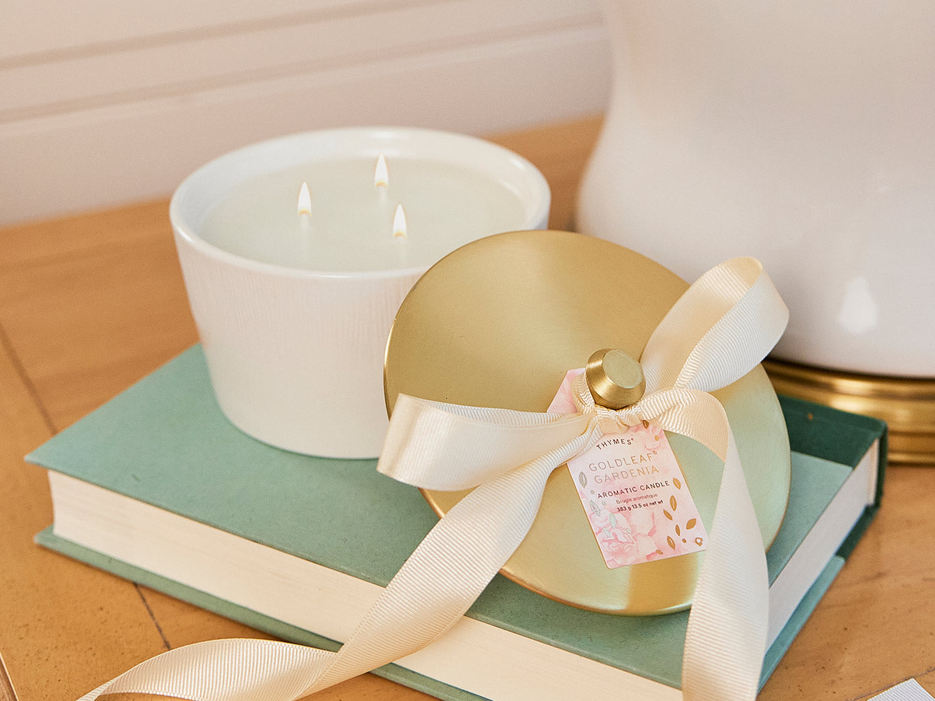 Magnolia Willow candle sitting on wooden end table with books and vase.