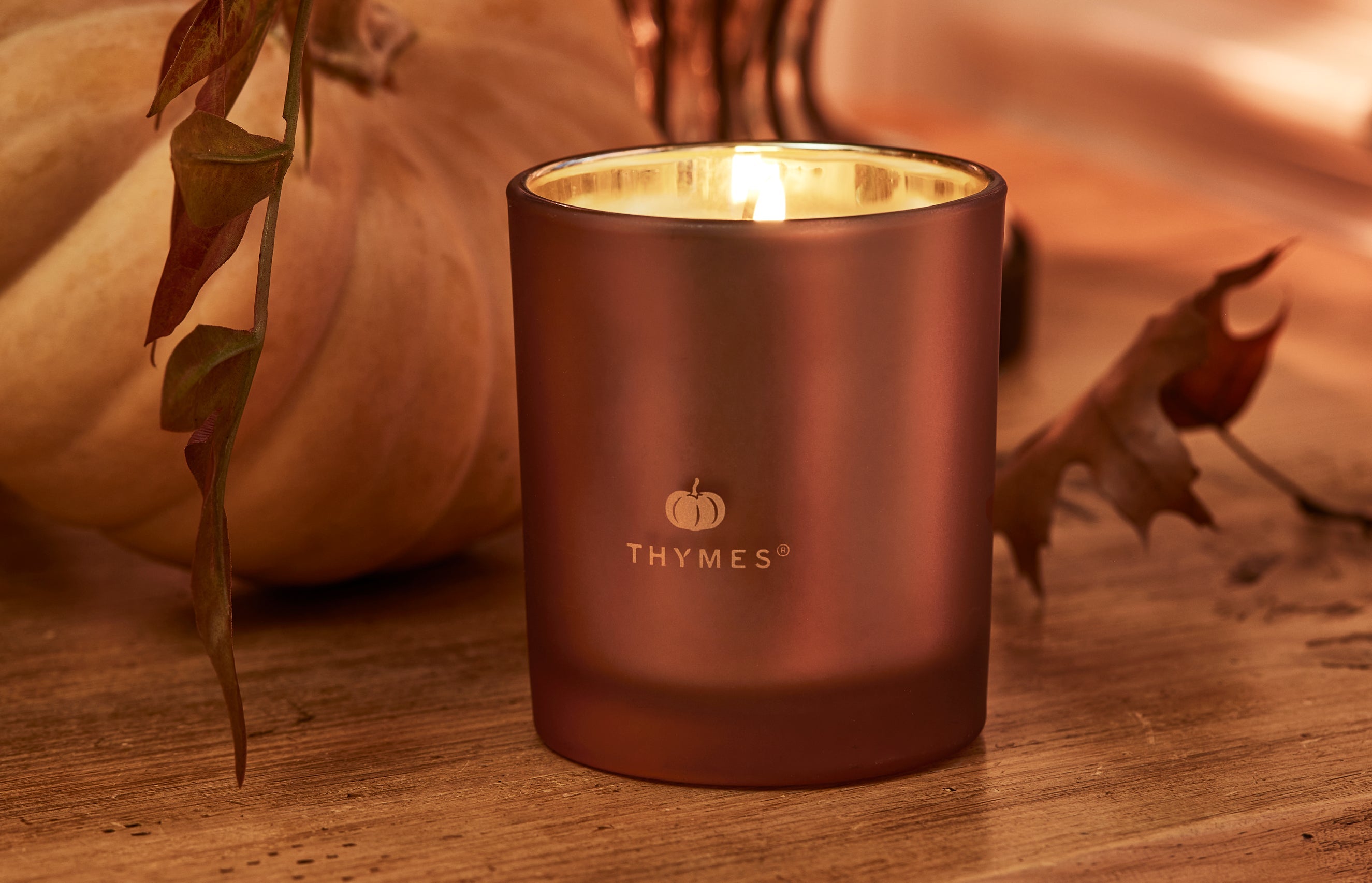 Magnolia Willow candle sitting on wooden end table with books and vase.