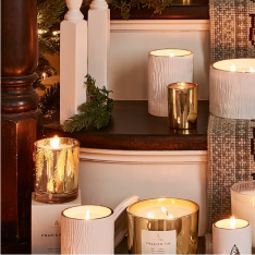 Magnolia Willow candle sitting on wooden end table with books and vase.