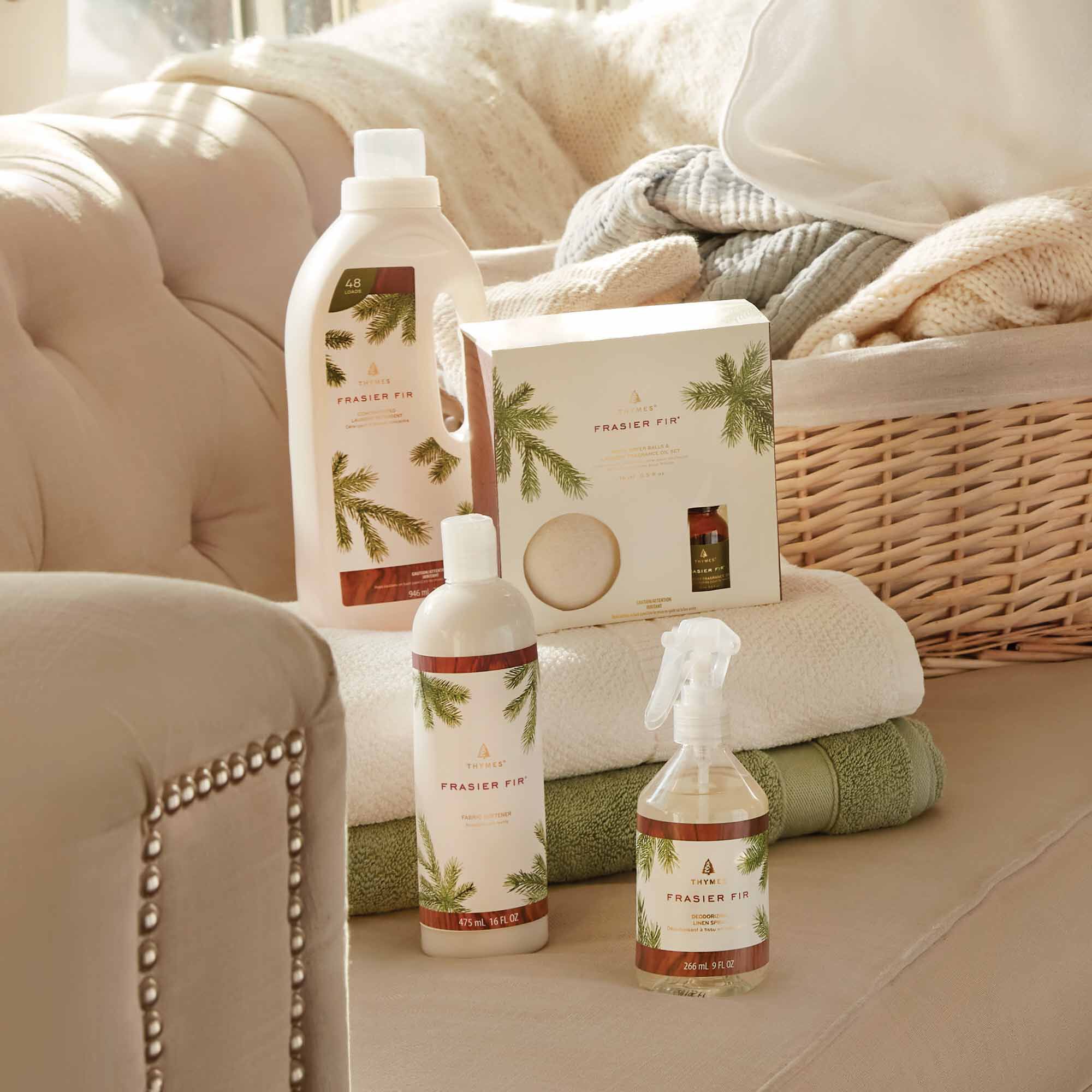 Thymes Frasier Fir Laundry Home Care products on a sofa atop a stack of fresh towels