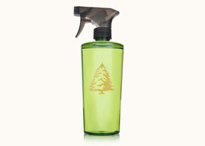 Thymes Frasier Fir Laundry Home Care products on a sofa atop a stack of fresh towels