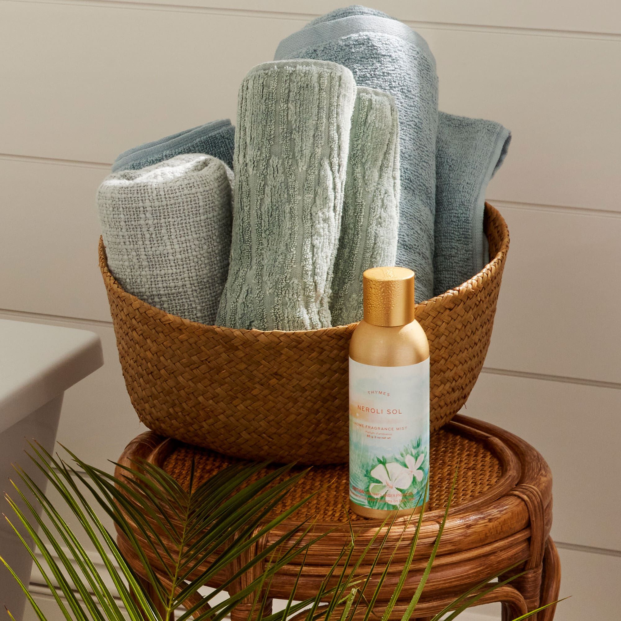 Thymes Neroli Sol Home Fragrance Mist on a wicker table with towels