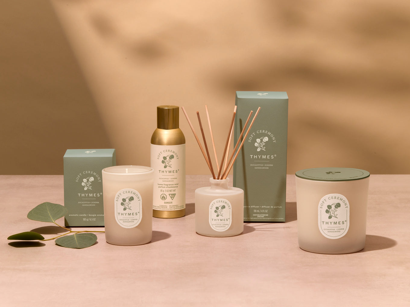 Collection of Thymes products including candles and diffuser on a beige background