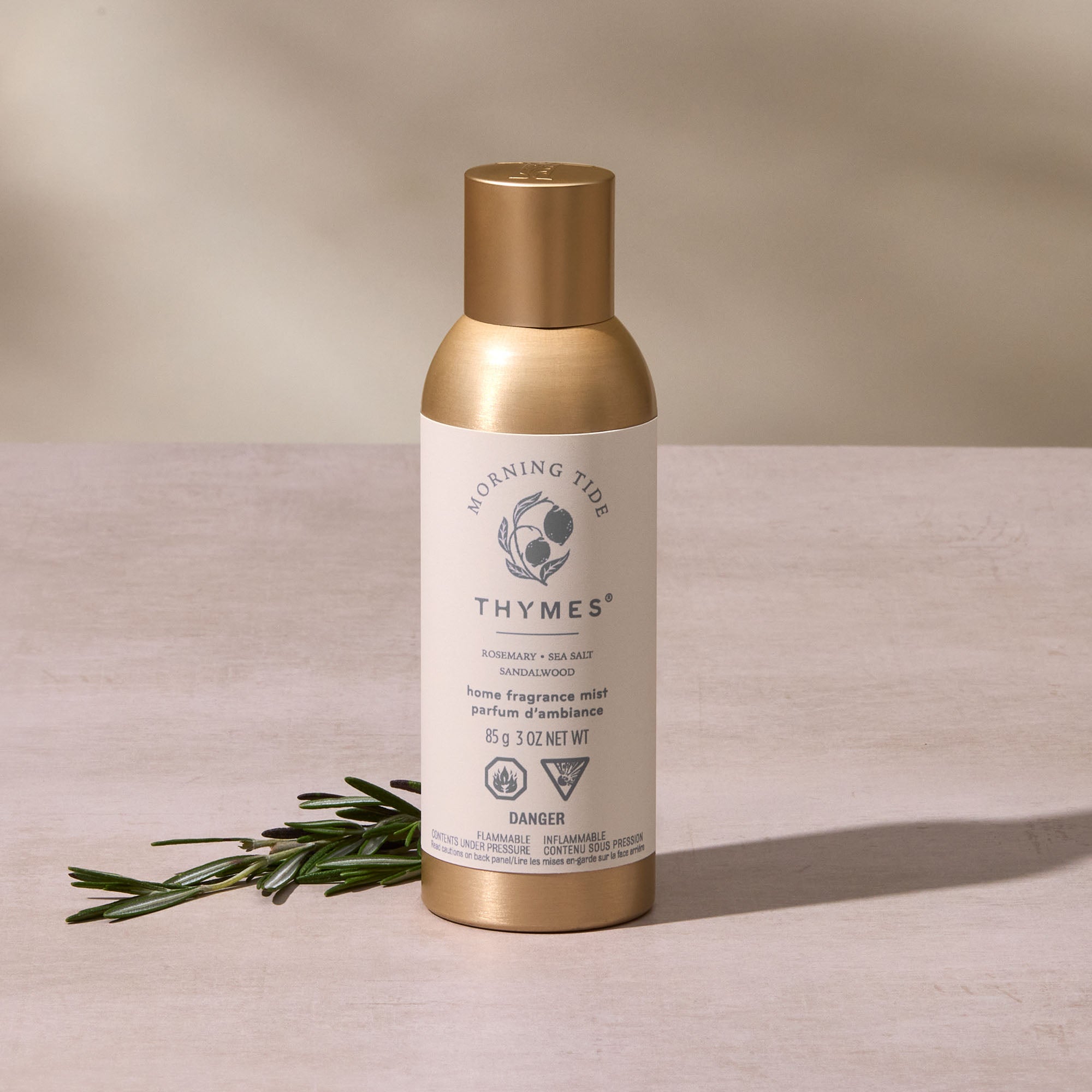 Thymes home fragrance mist bottle with gold cap on a beige background