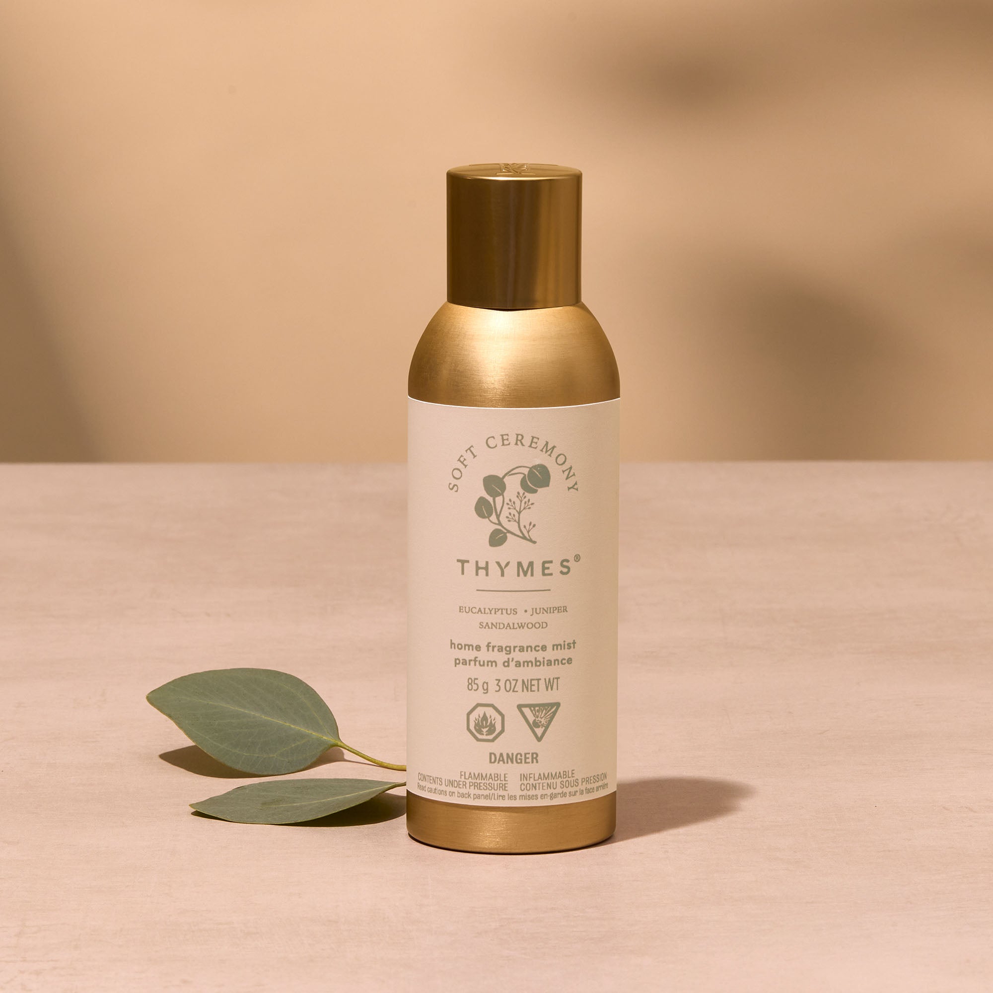 Thymes home fragrance diffuser bottle with gold cap on a beige background