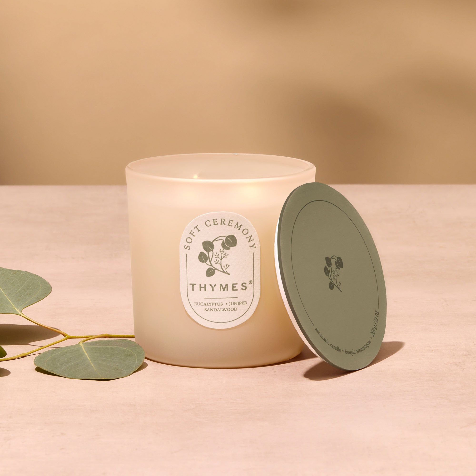 Thymes candle with a green lid on a beige background