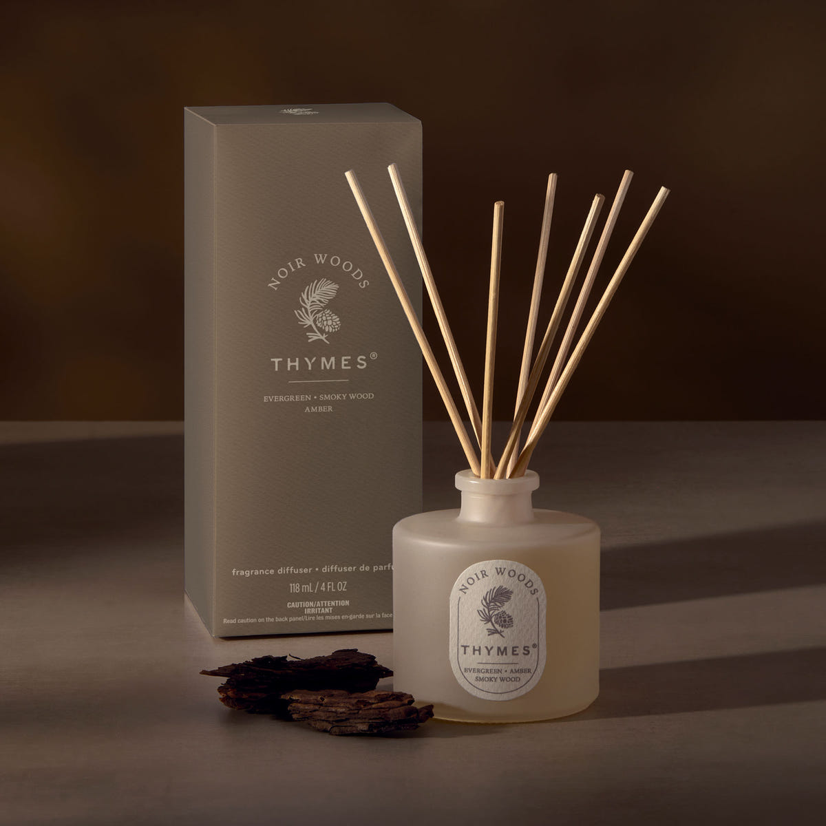 Alternate image of Thymes diffuser bottle with reeds and packaging on a dark background