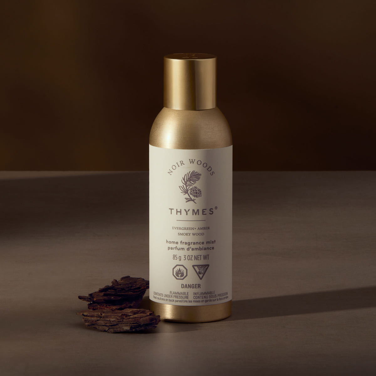 Thymes home fragrance mist bottle with gold cap on a brown background