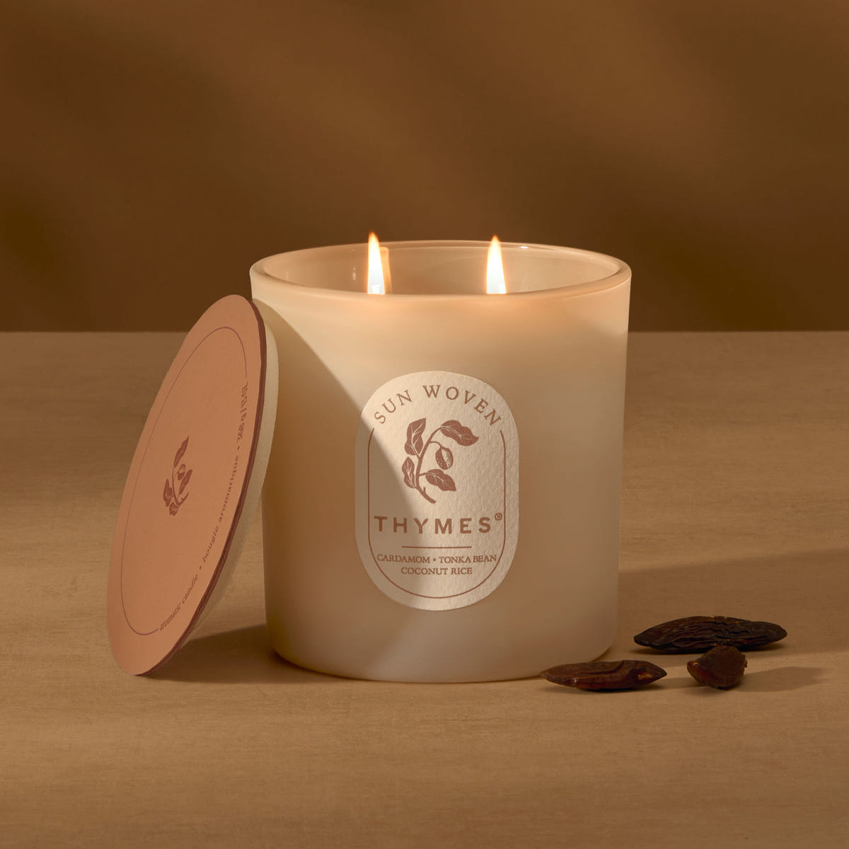 Alternate image of Thymes candle with a lit wick on a brown background