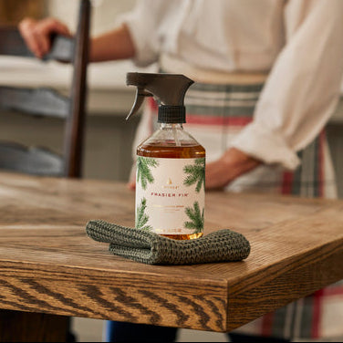 Cleaning product with a label on a wooden table, person in background