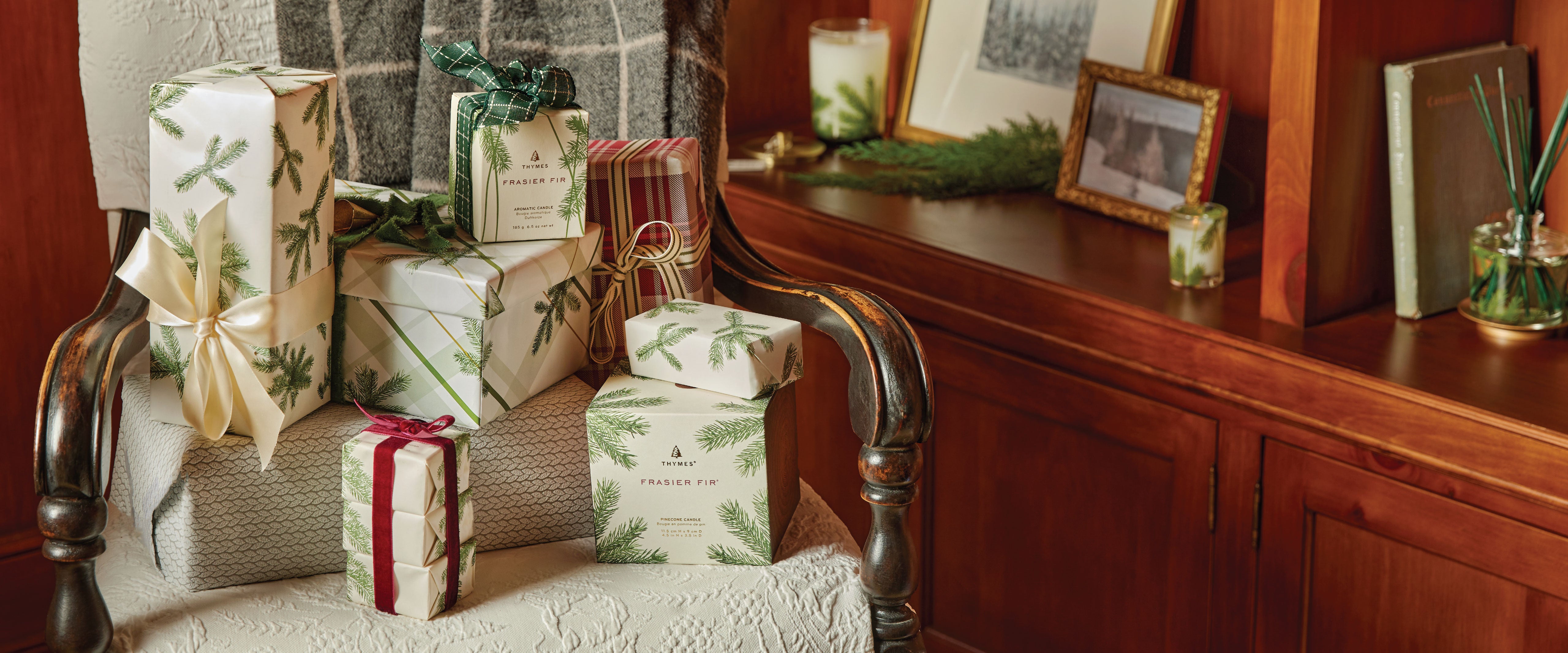 Frasier Fir gift-wrapped presents on a chair with a wooden sideboard in the background