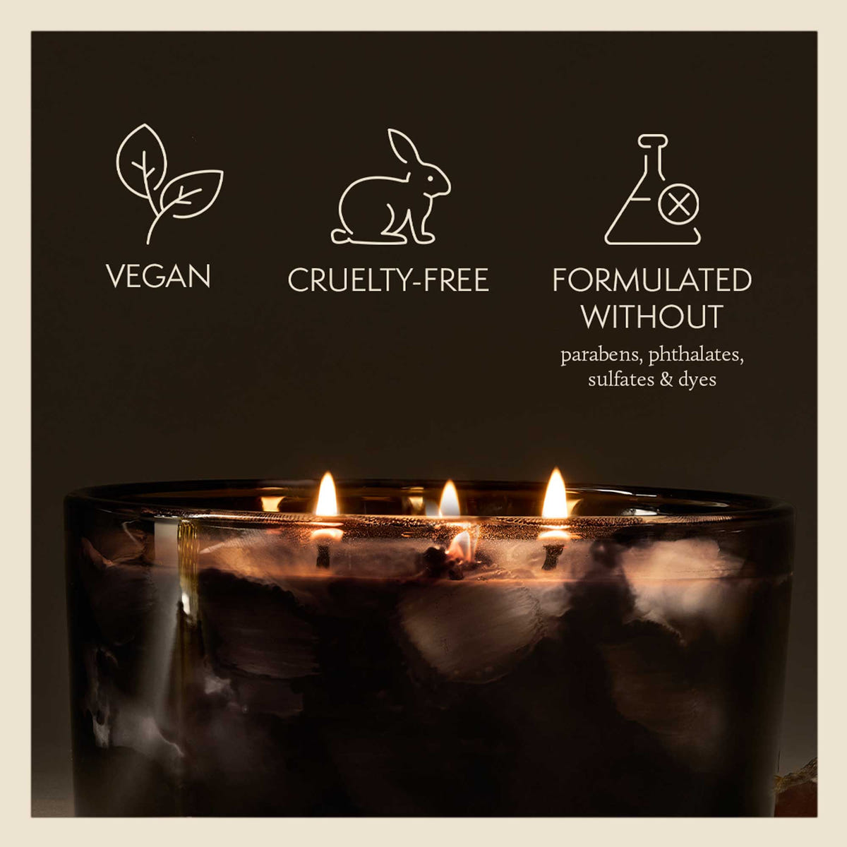 Candle with vegan, cruelty-free, and sulfate-free icons on a dark background