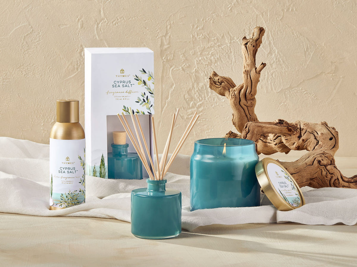 Teal candles and diffusers with packaging on a neutral background