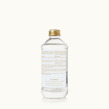 Clear bottle with gold cap on a white background, featuring the Thymes brand.