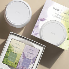 Pura smart fragrance diffuser set with eucalyptus and lavender refills on a beige surface.
