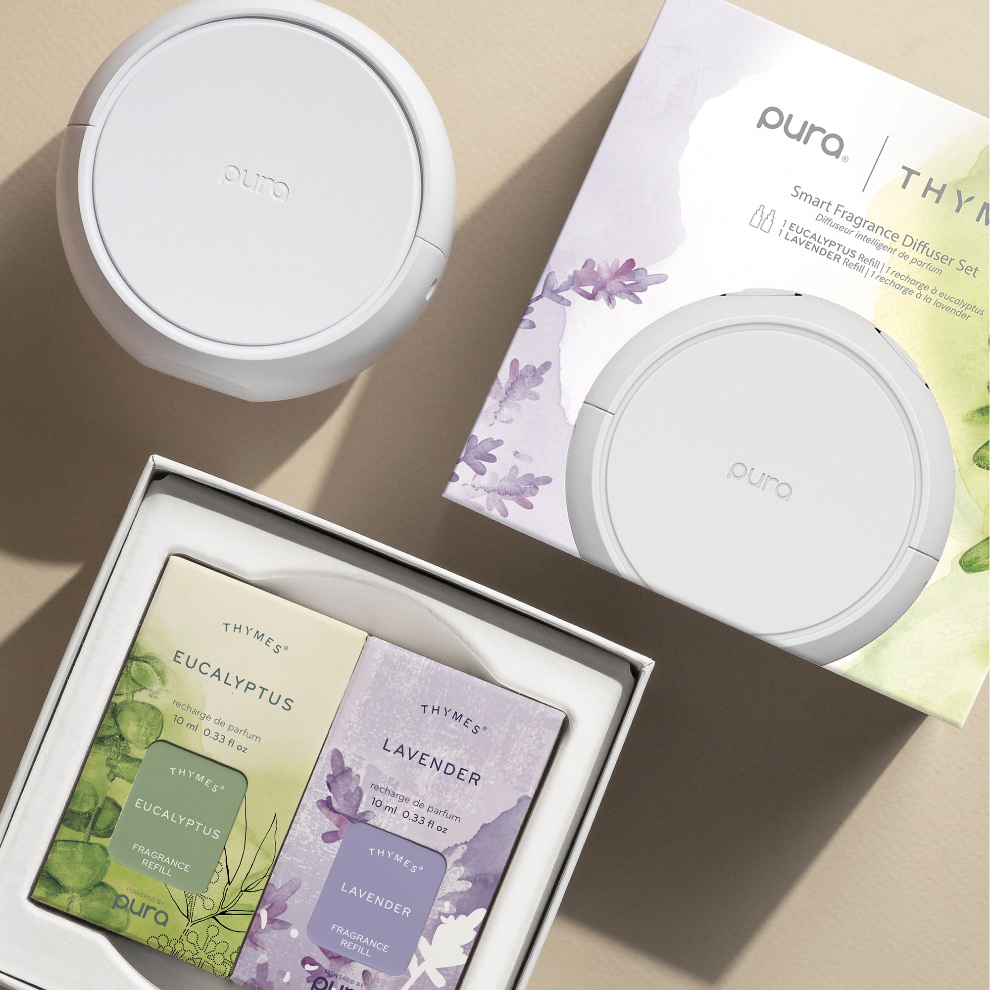 Pura smart fragrance diffuser set with eucalyptus and lavender refills on a beige surface.