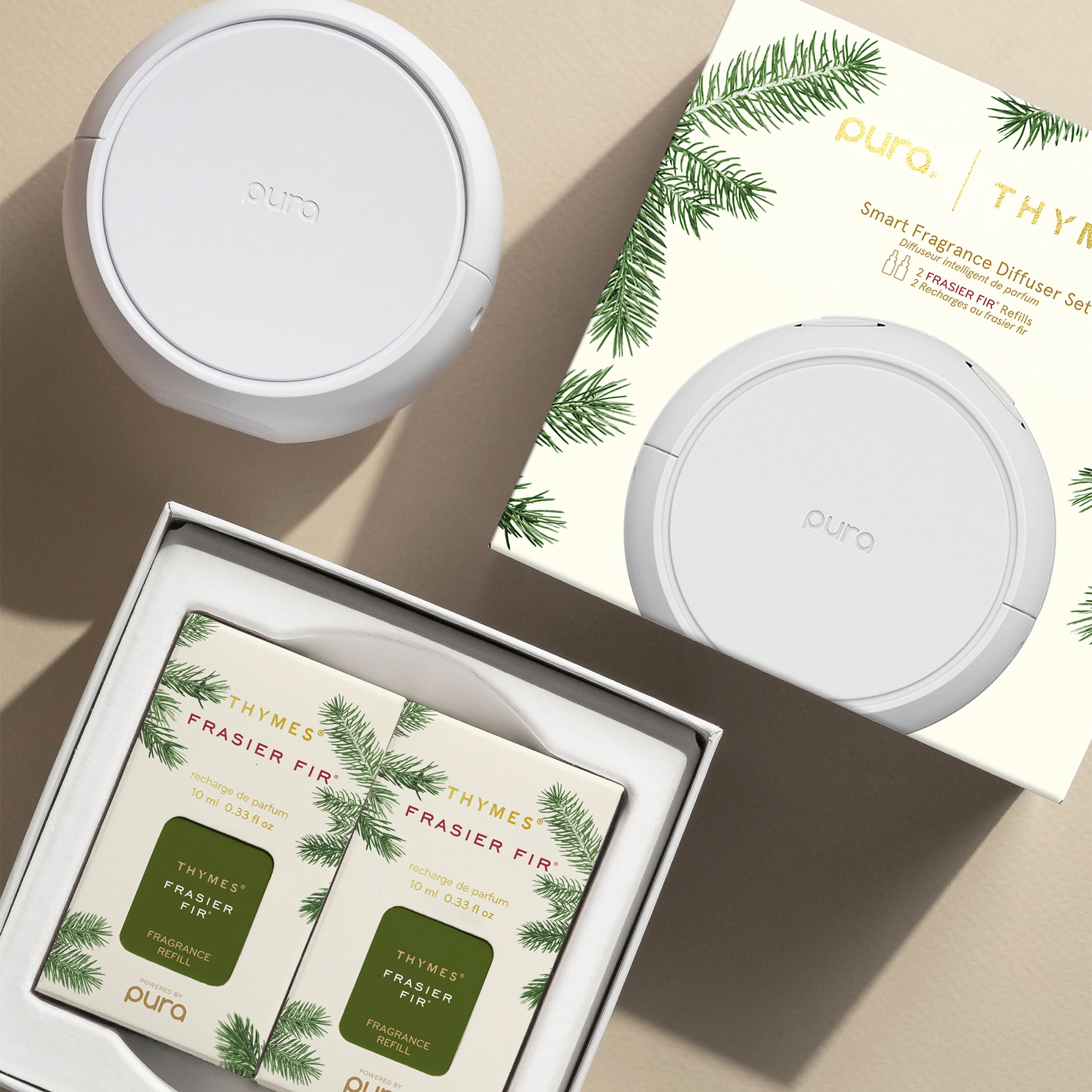 Pura smart fragrance diffuser set with Frasier Fir candles on a beige surface