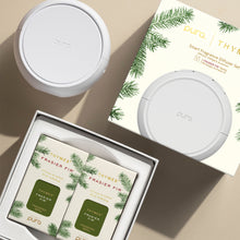 Pura smart fragrance diffuser set with Frasier Fir candles on a beige surface