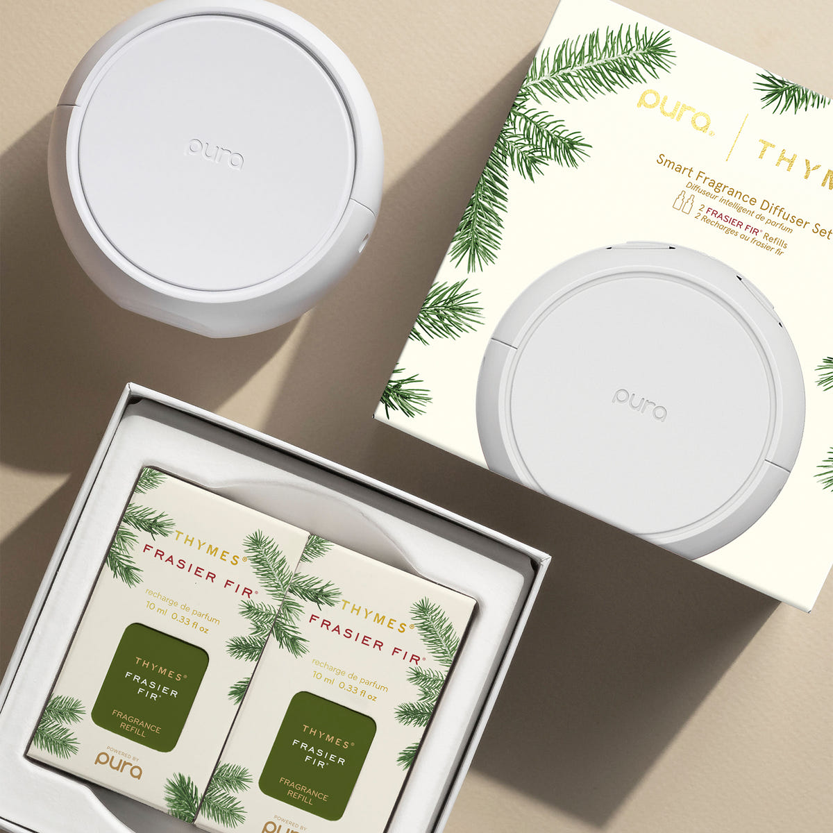 Pura smart fragrance diffuser set with Frasier Fir candles on a beige surface
