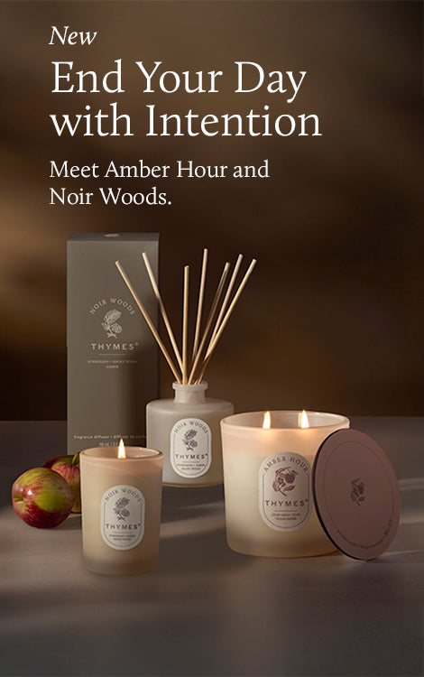 Thymes candles and diffuser with text 'New End Your Day with Intention Meet Amber Hour and Noir Woods' on a dark background