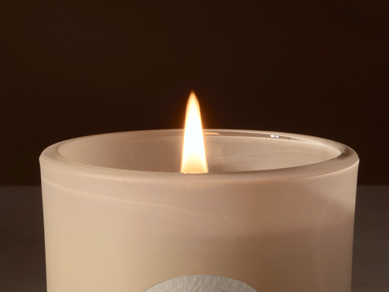 Candle in a white container with a dark background