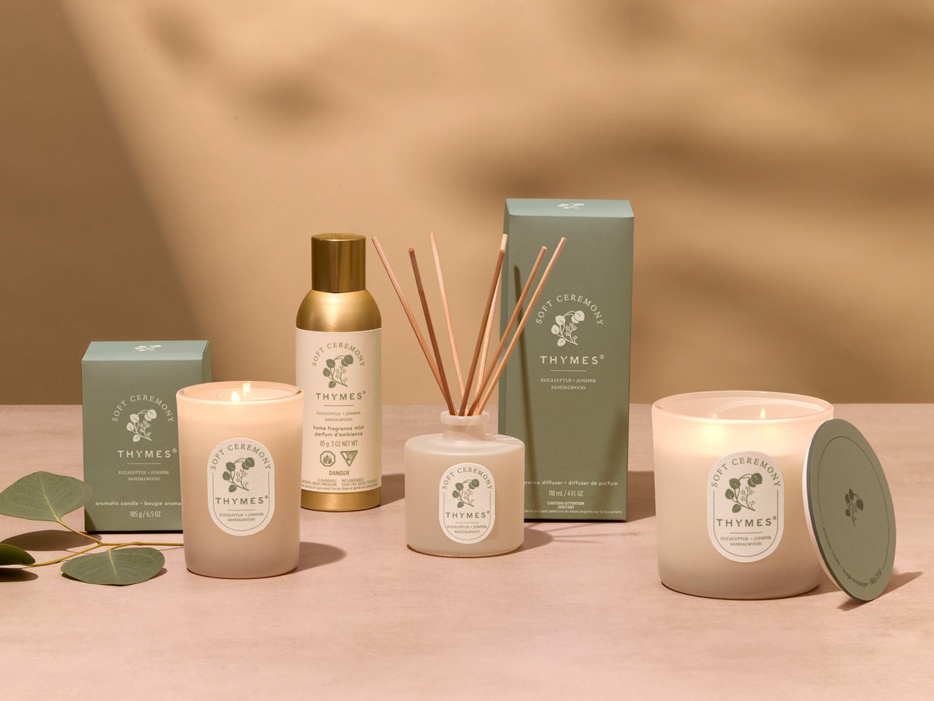 Thymes product line including candles, diffuser, and packaging on a neutral background