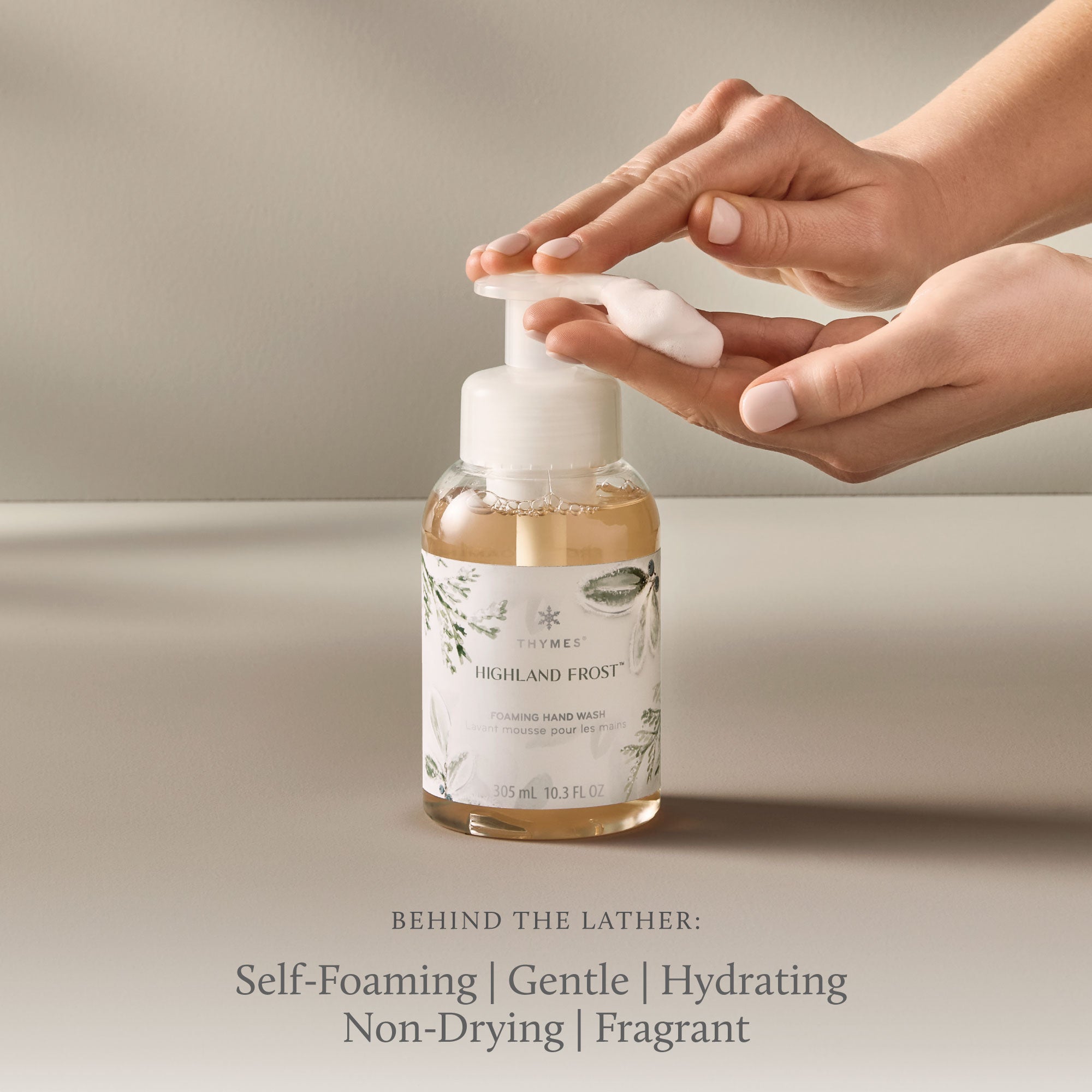 Hand using a self-foaming hand wash bottle with a neutral background
