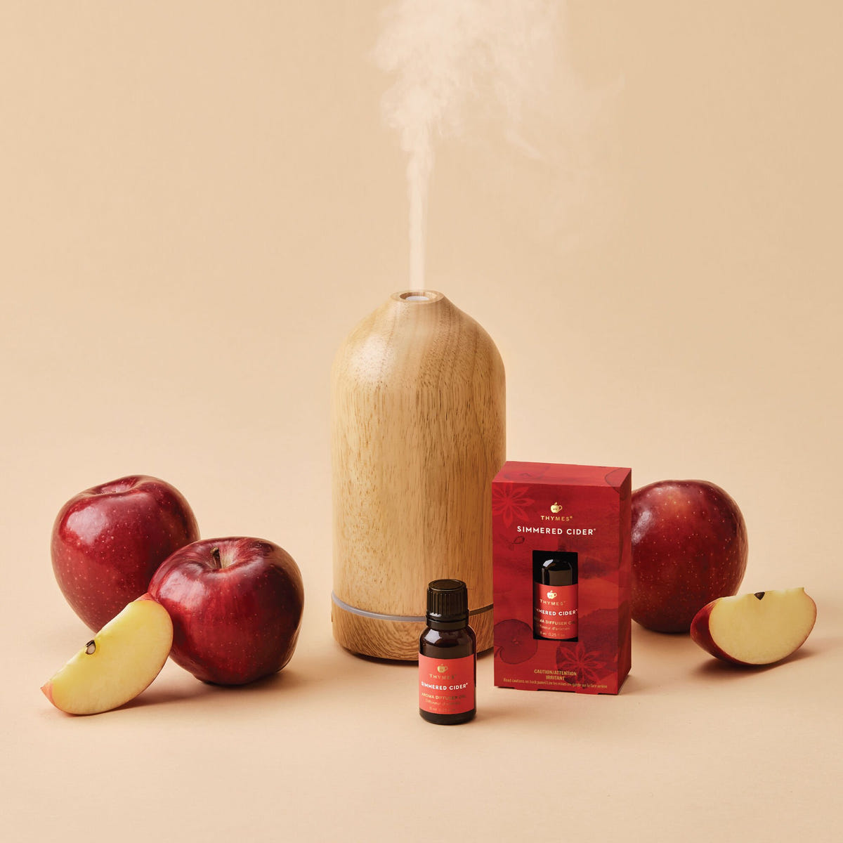 Alternate image of Thymes Simmered Cider Diffuser Oil Beside Electric Diffuser and Apples