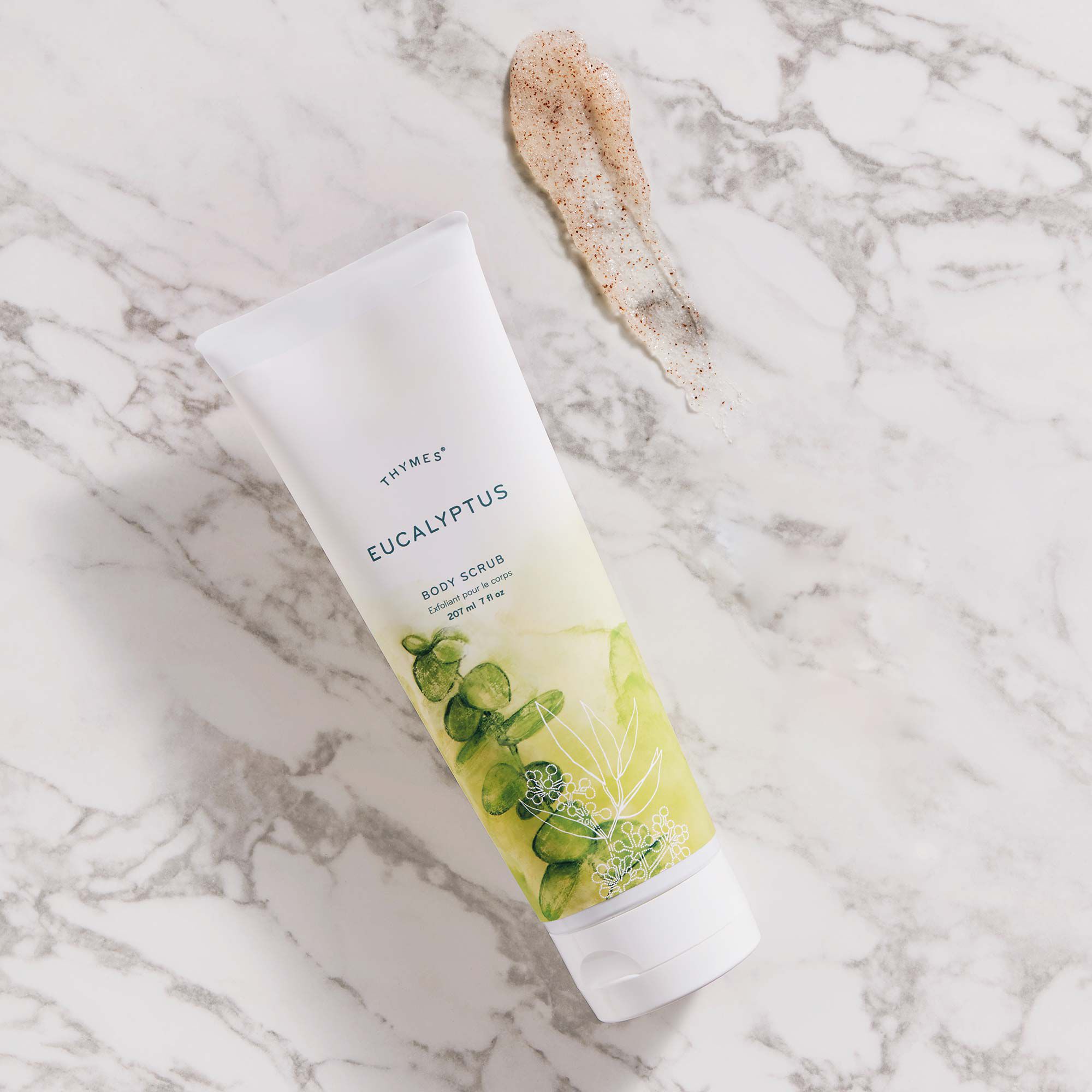 Thymes Eucalyptus Body Scrub on counter with Body Scrub product swipe