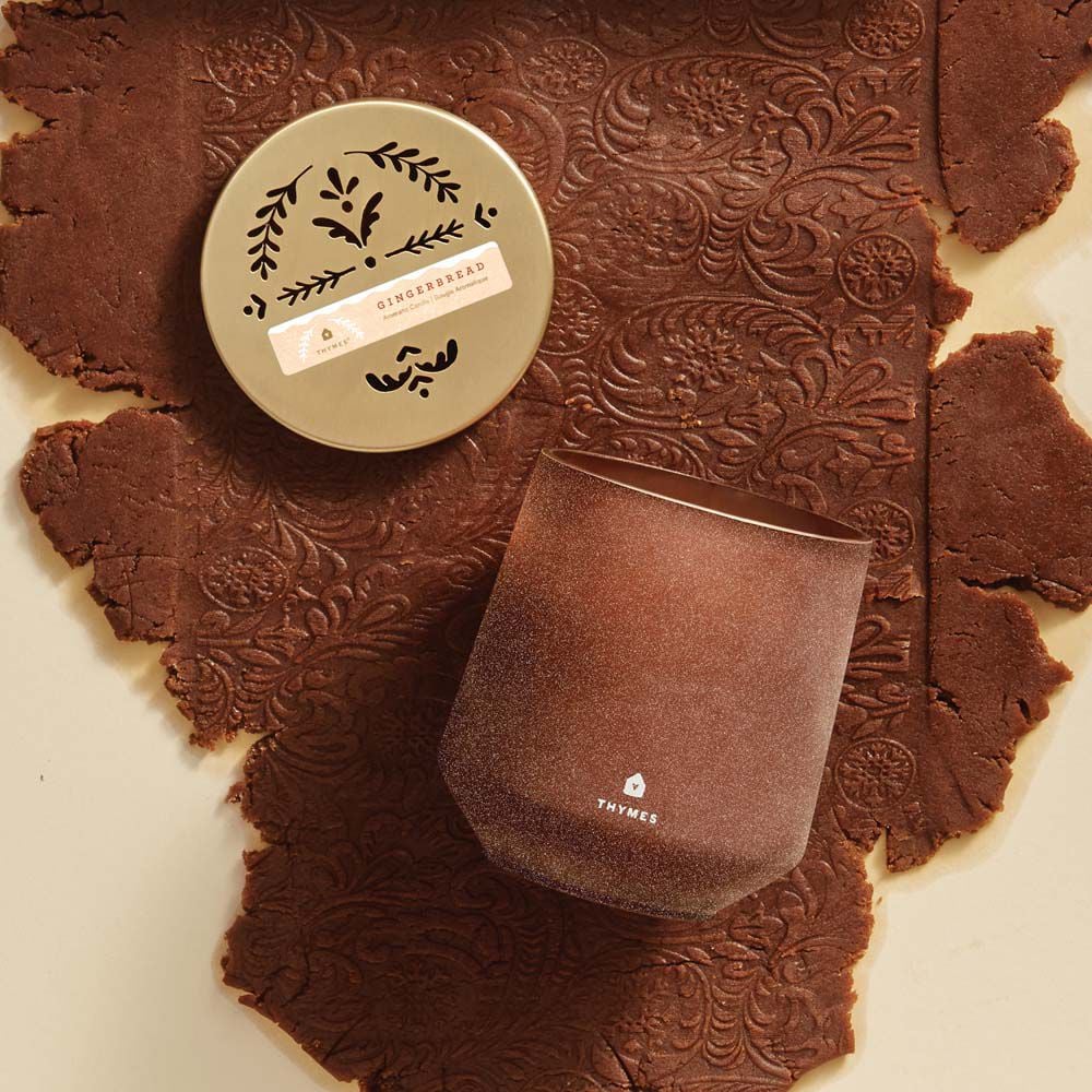 Alternate image of Thymes Gingerbread Large Candle is a Holiday Fragrance laying on decorative gingerbread dough