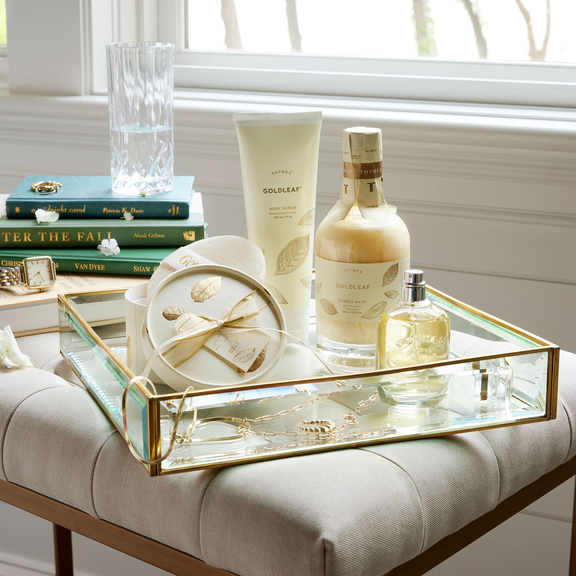 Thymes Goldleaf Bubble Bath on glass tray next to Thymes Goldleaf bath and body products