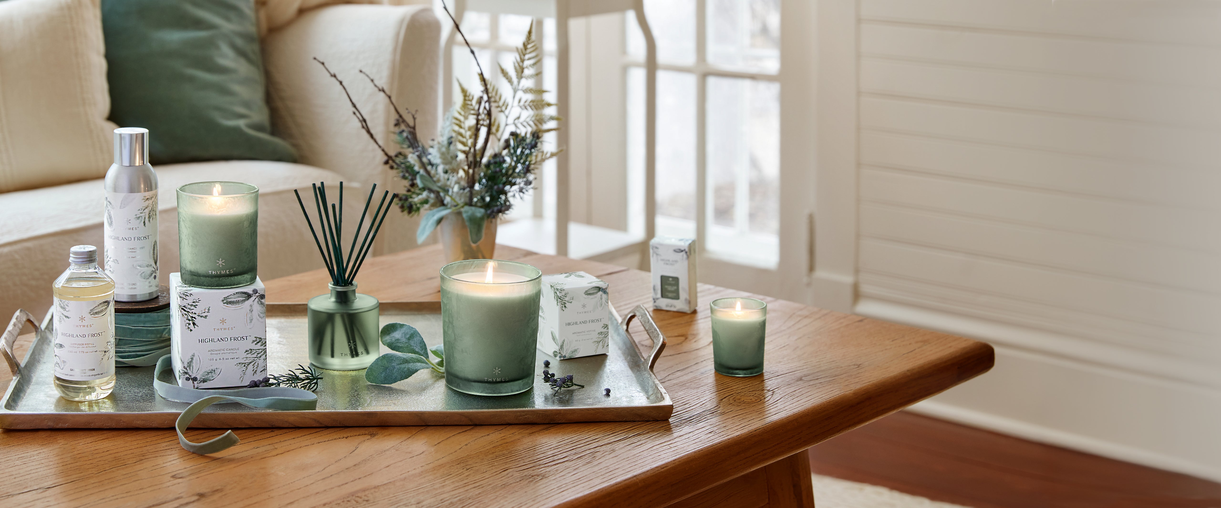 Candles and diffusers on a tray with a view of a living room.