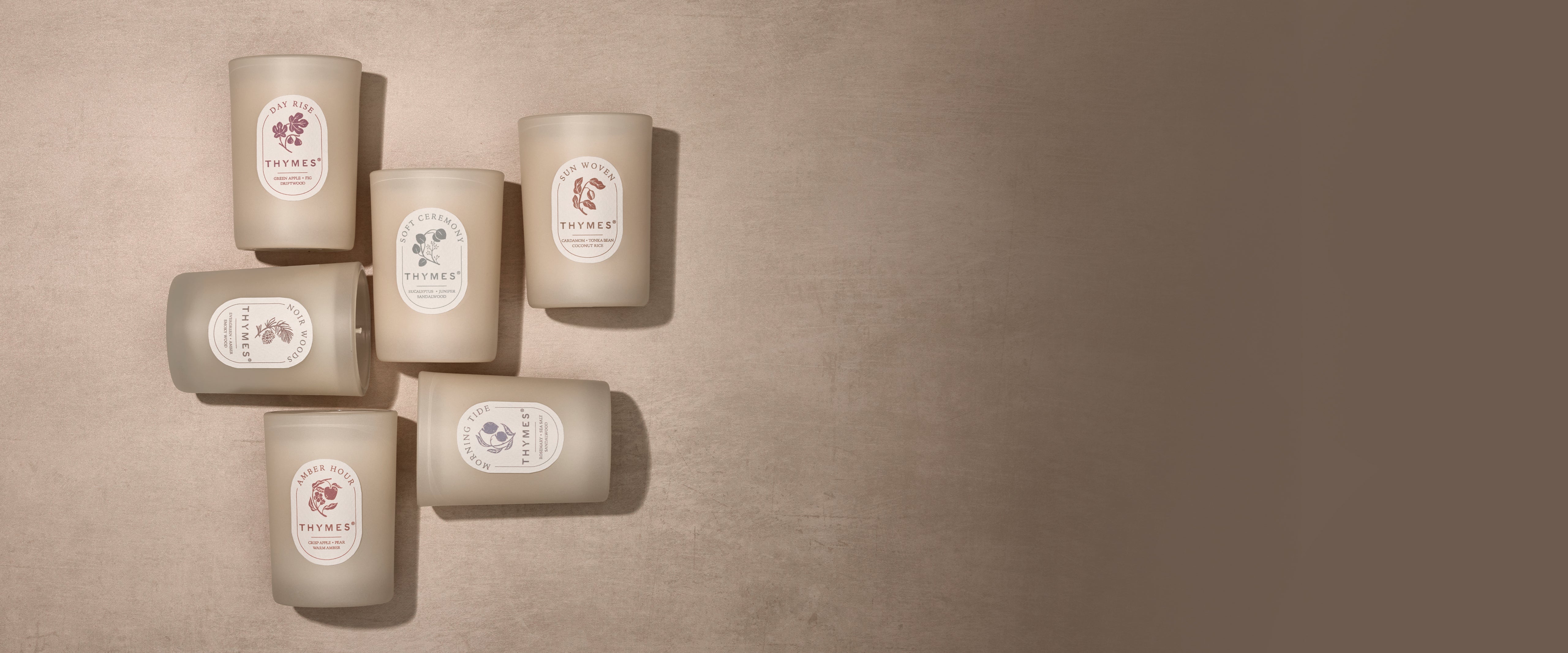 Set of six cylindrical candles with labels on a beige background