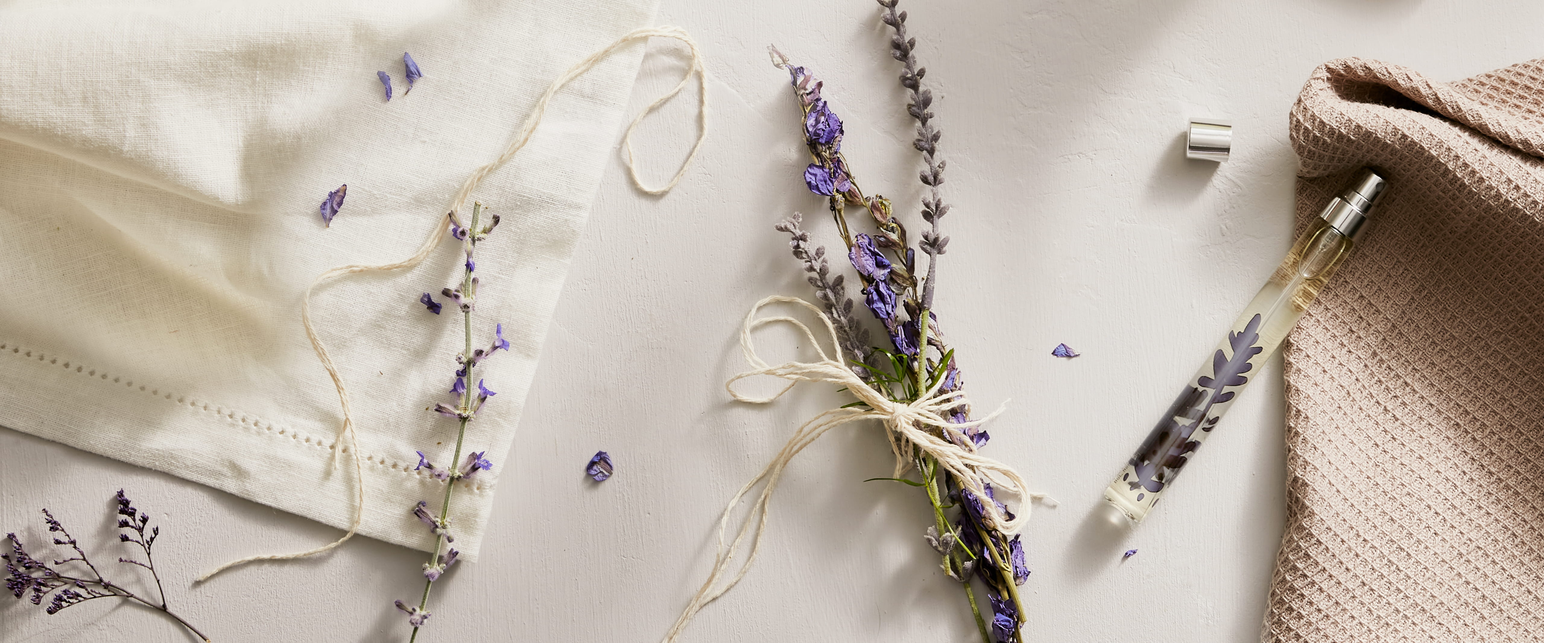 Lavender flowers and a face mask on a light surface