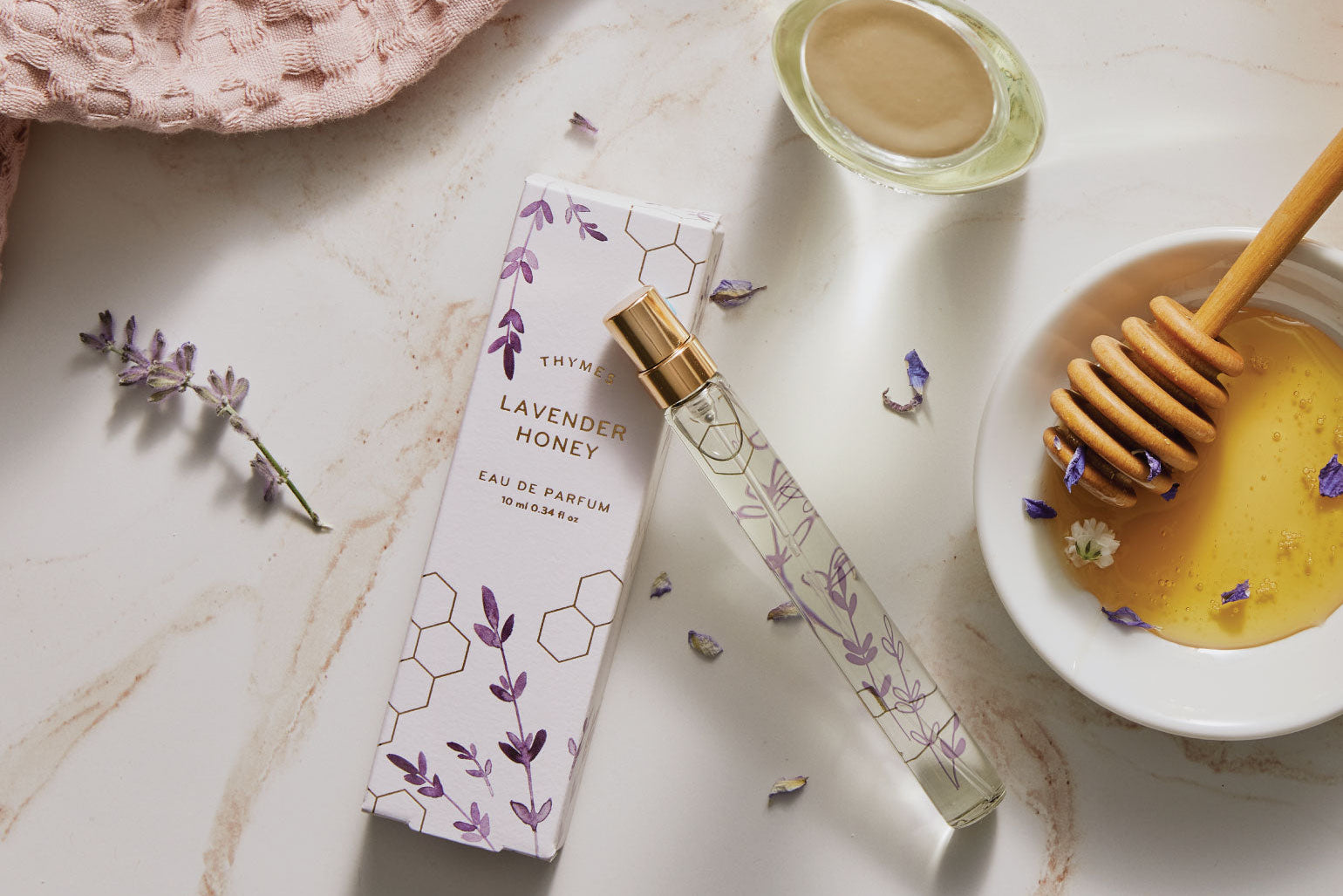 Lavender Honey perfume  spray pen and packaging on a marble surface with honey and lavender.