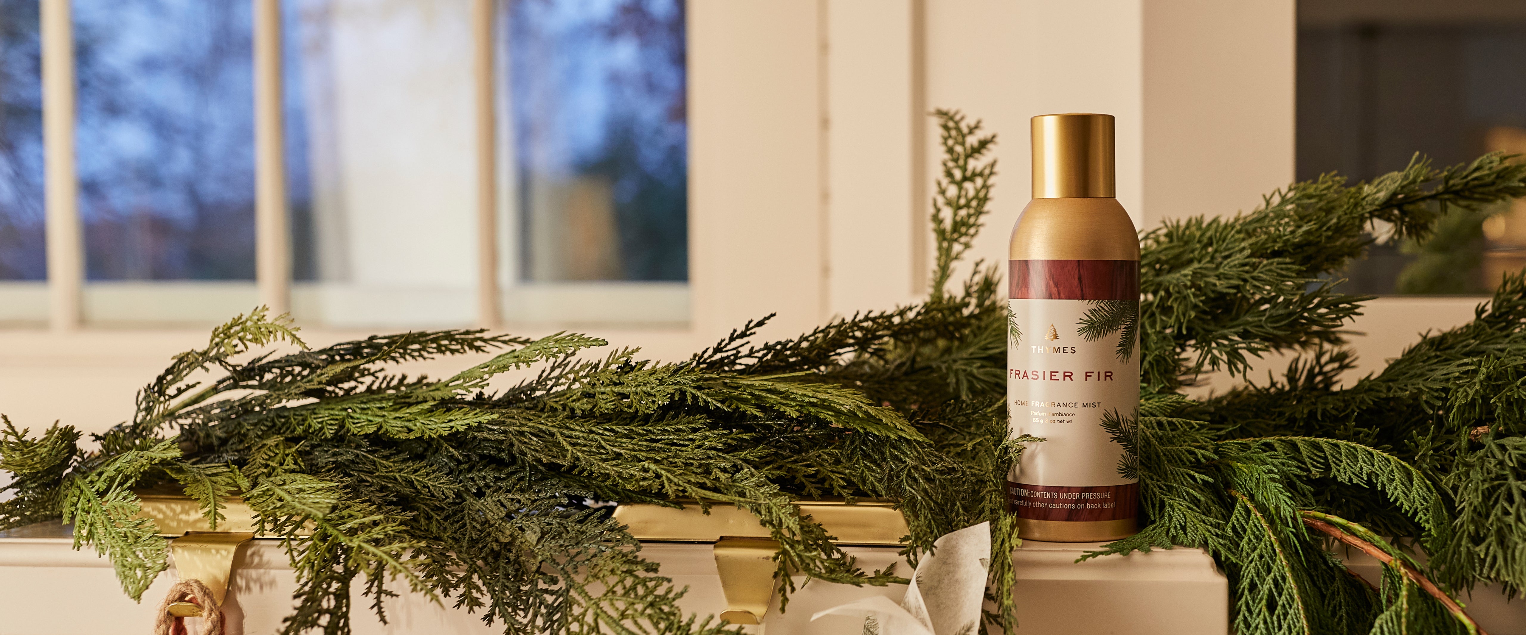 Bottle of Frasier Fir Home Fragrance Mist on a decorative fireplace mantel with greenery