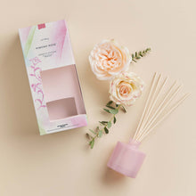 Thymes Kimono Rose Petite Reed Diffuser next to roses