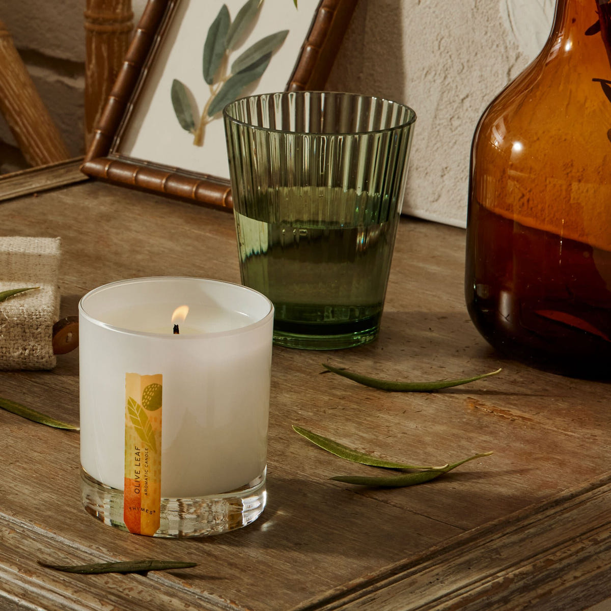 Alternate image of Thymes Olive Leaf Candle in Glossed Ceramic Jar featured on table with vases