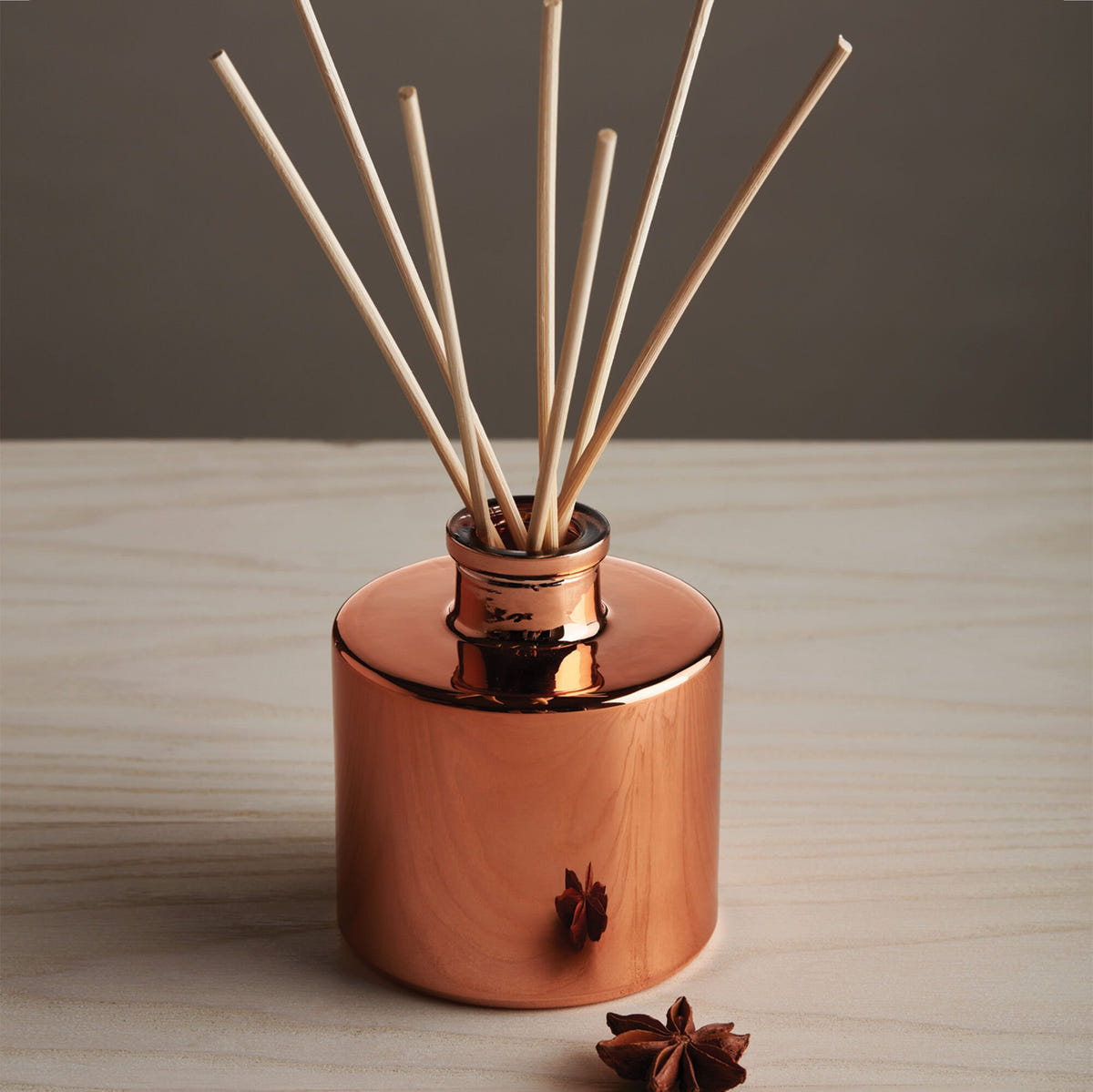 Alternate image of Simmered Cider Petite Reed Diffuser on a wooden surface