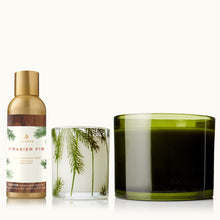 Three Thymes decorative items including a home fragrance mist, a green glass candle, and a pine needle candle on a tan background