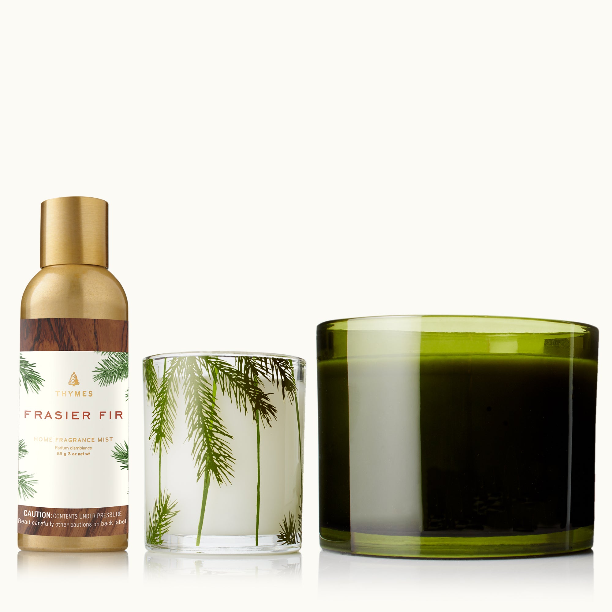 Three Thymes decorative items including a home fragrance mist, a green glass candle, and a pine needle candle on a tan background
