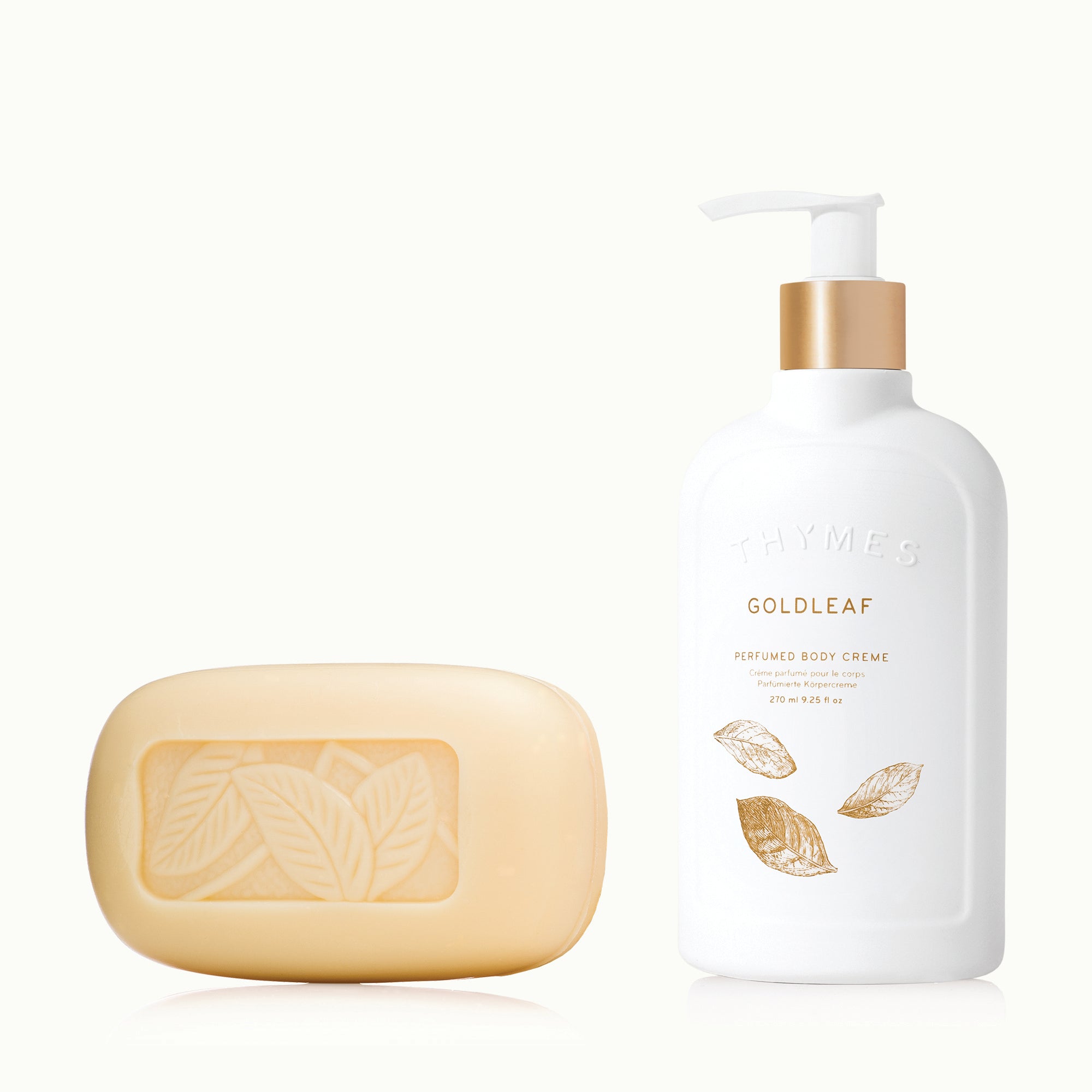 White bottle of Goldleaf body crème and a bar of soap on a white background