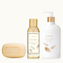 Three Goldleaf bath products including a bar of soap, a bottle of home fragrance mist, and a pump bottle of body cream on a white background.