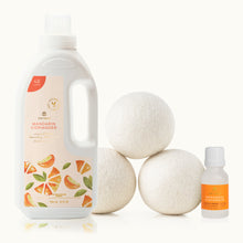 Thymes Mandarin Coriander laundry detergent bottle, dryer balls, and essential oil bottle on a white background