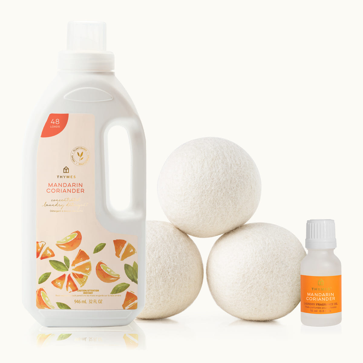 Thymes Mandarin Coriander laundry detergent bottle, dryer balls, and essential oil bottle on a white background