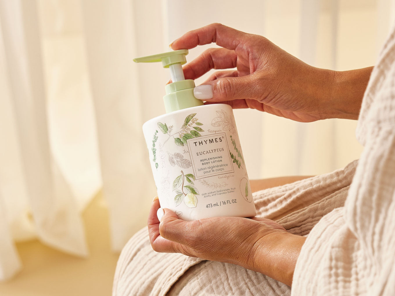 Person holding a Thymes eucalyptus body lotion with a blurred background