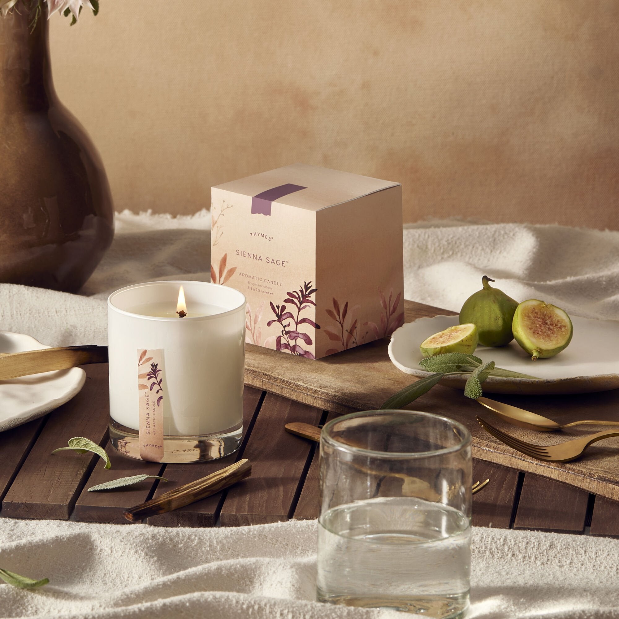 Thymes Sienna Sage Candle on dining table with figs